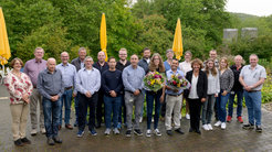 Den Azubis Jara Voigt und Amrit Poudel (beide mit Blumensträußen) wurde von der Geschäftsführenden Direktorin Marina Rodnina (rechts daneben) die Auzeichnung überreicht. Die Ausbilder*innen am Institut sowie Gäste waren bei den Feierlichkeiten anwesend. Preisträgerin Julia Thiemann konnte leider nicht dabei sein.